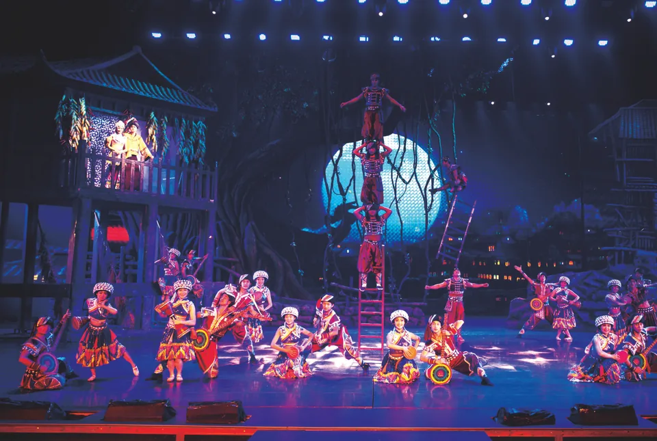 Group dancers, wooden-building scenery and blue lighting on the Charming Xiangxi stage