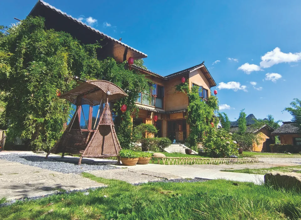 Wooden house, garden and courtyard swing under a blue sky